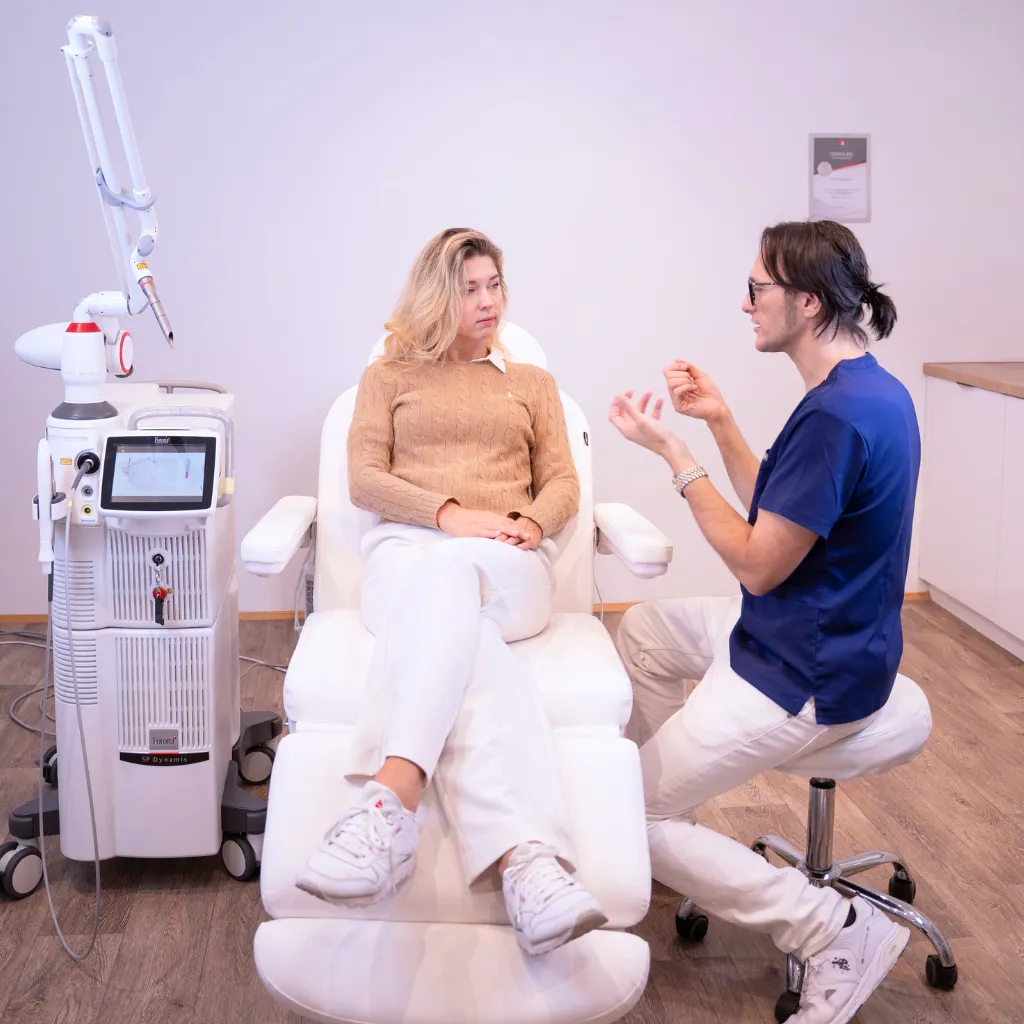 Dr. Modar Koujan im Beratungsgespräch mit einer Patientin neben dem Lasergerät