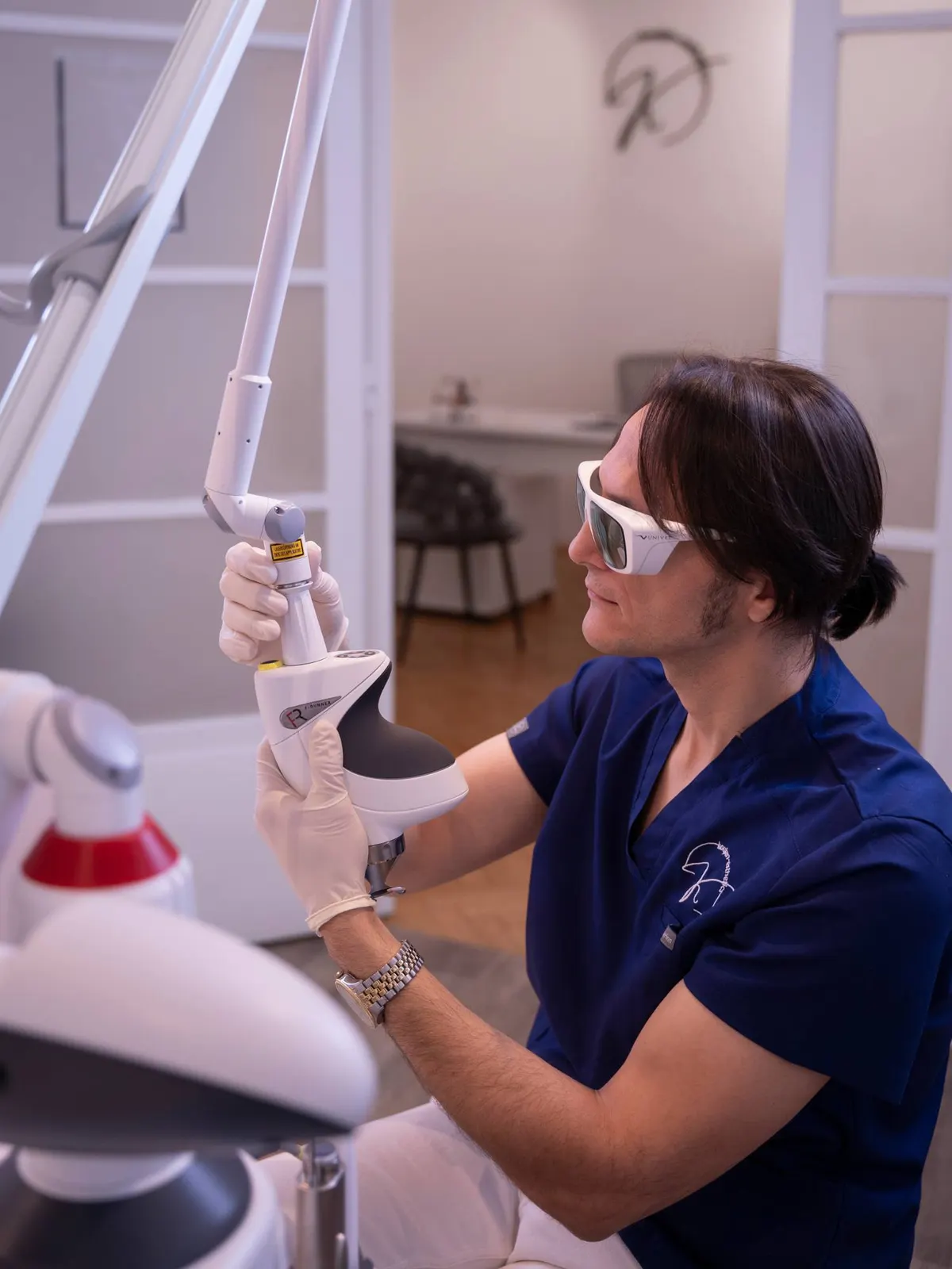 Dr. Modar Koujan mit Schutzbrille am Lasergerät in seiner Ordination